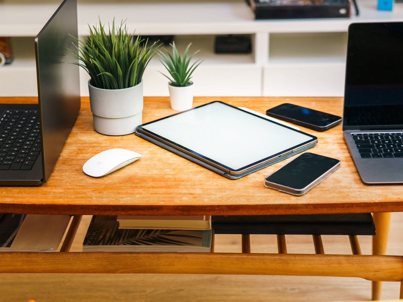 A laptop, a tablet and a phone side by side on a wooden desk